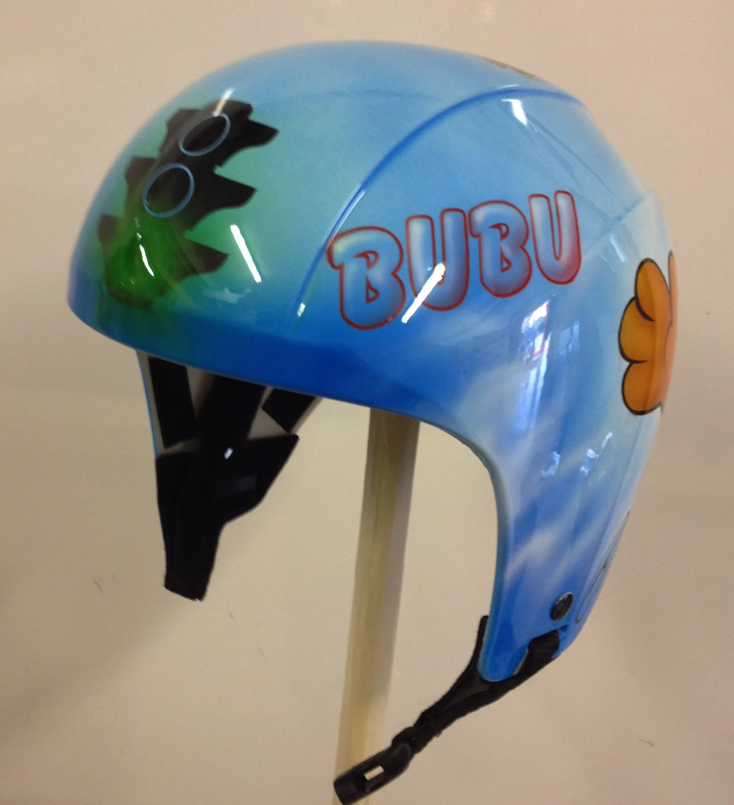 Un volto per il volo. &mdash; Un casco da parapendio decorato con un personaggio illustrato e colori dedicati.